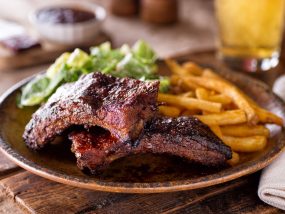 A plate of delicious barbecued ribs with french fries and salad.